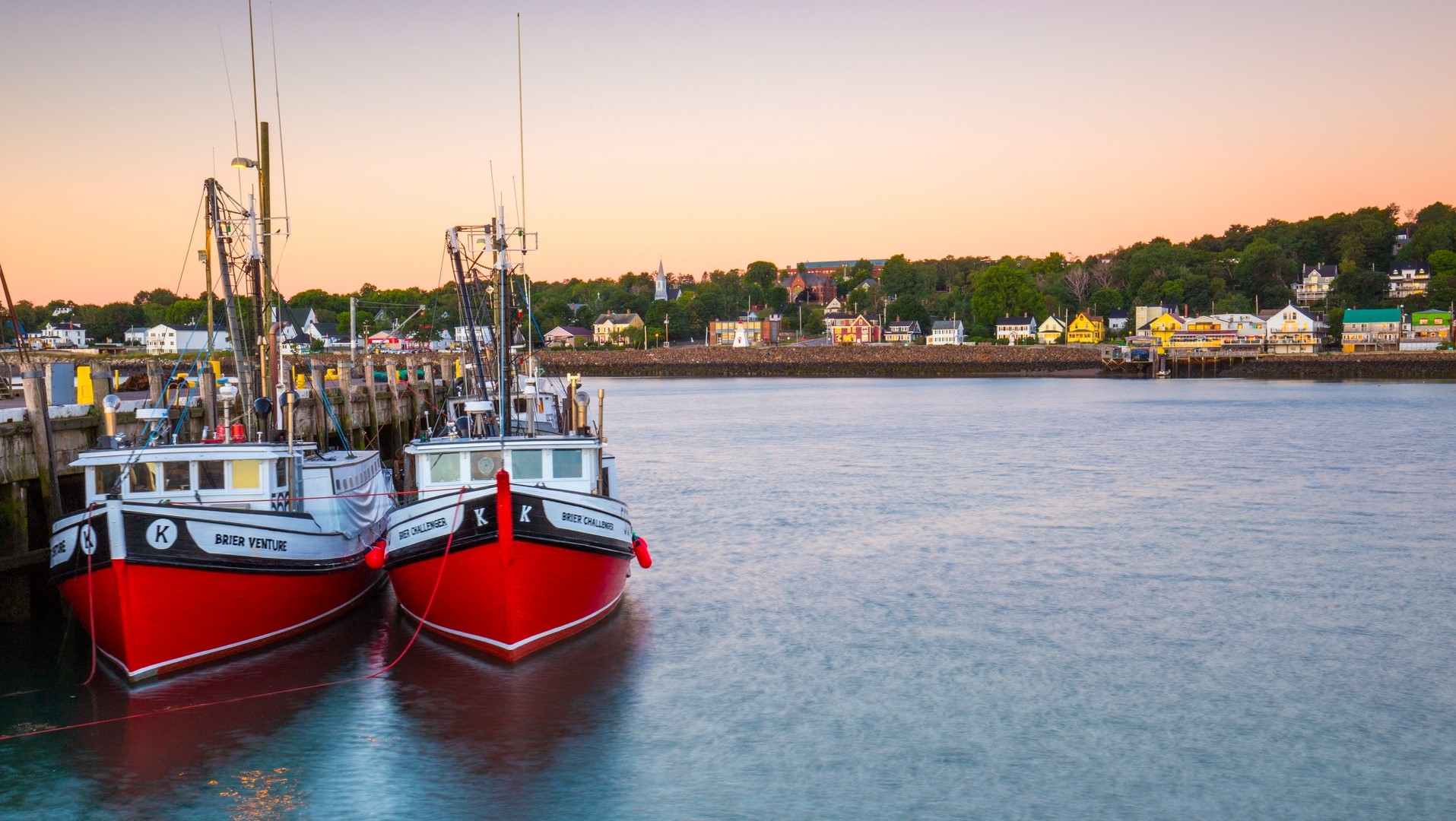 Two red fishing boats tied at the wharf at sunset
